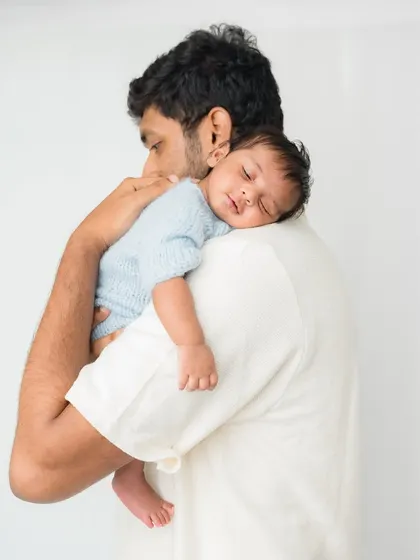 A peaceful moment of a newborn sleeping soundly on his father's shoulder.