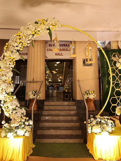 The entrance to the Mehendi hall, featuring a beautiful floral arch in white and yellow. A grand entrance sets the stage for the celebration inside.