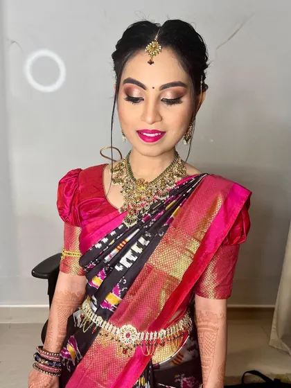 A close-up of Bhanu's makeup. The focus is on her shimmering bronze and gold eyeshadow, perfectly blended to create a sophisticated look that complements her vibrant saree.