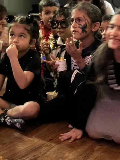 Snack time during the show! A group of kids, some with spooky face paint, sit mesmerized by the entertainment while enjoying their treats.