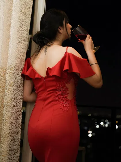 A beautiful shot in a red gown, enjoying a glass of wine with a city view. The back detail of the dress is the star here.