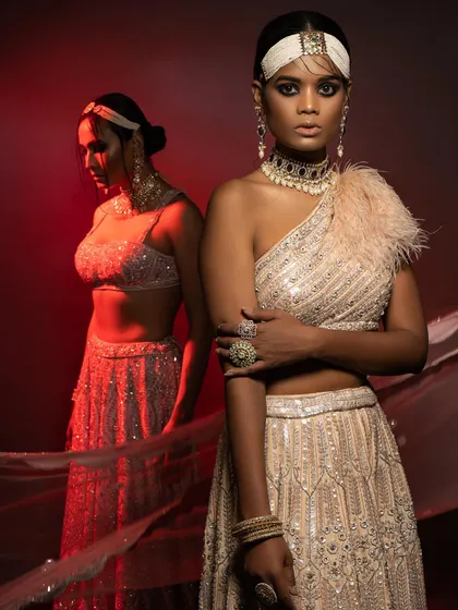 From a high-fashion editorial, this image uses dramatic red backlighting to create a powerful silhouette. I styled this sequined one-shoulder lehenga with a feather detail to blend modern glamour with traditional Indian design.