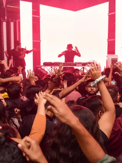 A view from the dance floor, looking up at two DJs on stage. A powerful image of the artists commanding the room.