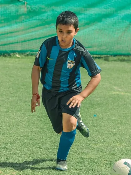A player in a blue and black striped jersey dribbles forward.