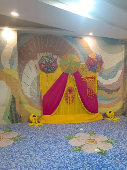 A poolside Haldi setup with a backdrop of yellow and pink drapes, decorated with Rajasthani umbrellas. The colorful mosaic tiles of the pool area complement the festive decor.