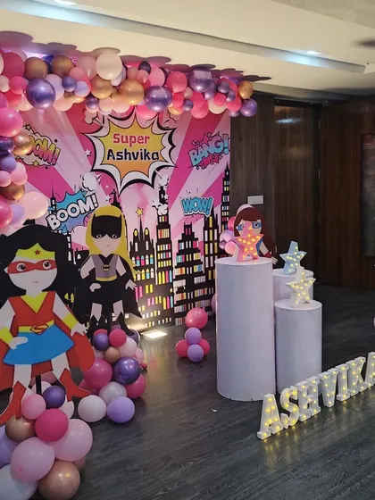 Another angle of the super-girl themed party, highlighting the balloon columns topped with character cutouts.