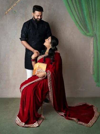 A classic, romantic portrait. The couple shares a look of love, dressed in beautiful red and black traditional attire.