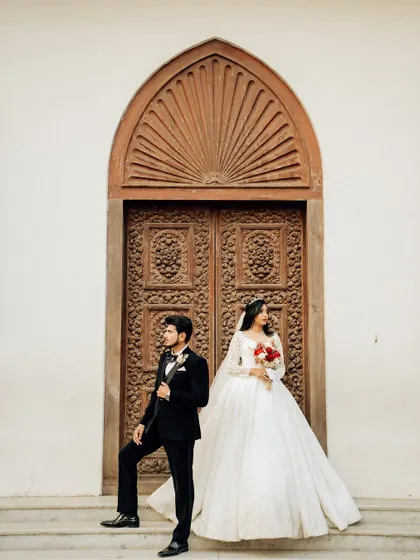 An editorial-style portrait with the couple posed against a grand, carved wooden door. This creates a dramatic and sophisticated wedding photograph.