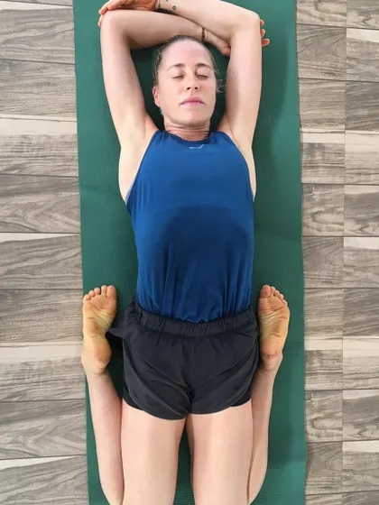 A guest relaxes in Supta Baddha Konasana (Reclining Bound Angle Pose). This restorative posture is excellent for opening the hips and promoting a state of deep relaxation and surrender.