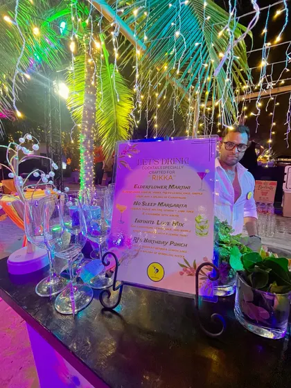Another example of a personalized menu for a birthday party, set against a beautifully lit bar. The menu features custom drink names like 'Rikka's Elderflower Martini' and 'Infinite Love Mix'.