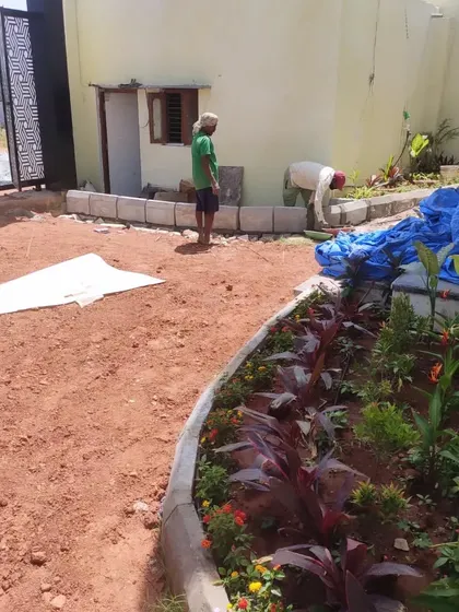 Here you can see the construction of a raised garden bed using concrete blocks. The surrounding area is being prepared for either a lawn or pathway.