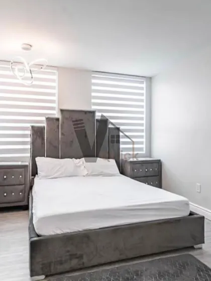This bedroom showcases a dramatic, high-back grey upholstered bed. The design is clean and modern, with simple nightstands and contemporary lighting, proving that a single, well-designed piece of furniture can define an entire room.