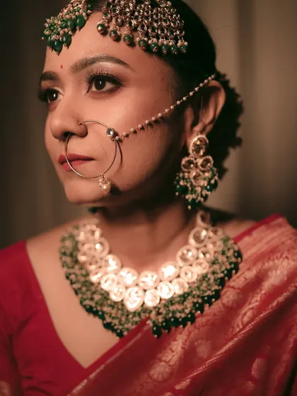 A detailed shot of the bride's stunning kundan and emerald jewelry and her traditional nath.