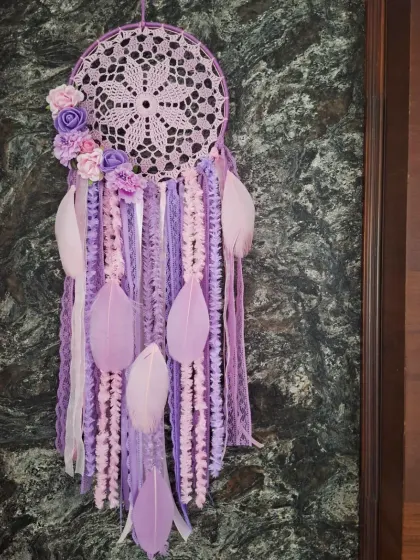 The perfect combination of lavender and lilac hues in this floral dreamcatcher brings cozy, pastel vibes to any room. The crochet work and feather details make it a whimsical piece of wall art.