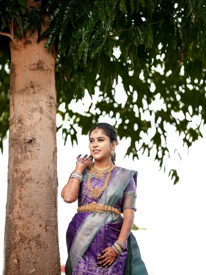 A full-length portrait of the bride-to-be, showcasing her elegant purple silk saree.