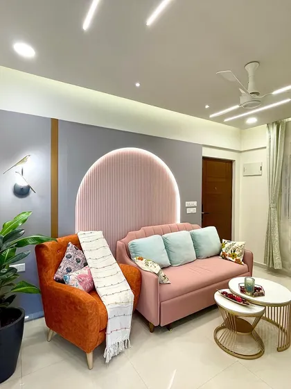 An orange armchair adds a bold pop of color, while the nested coffee tables with marble tops and gold frames bring a touch of modern glamour to the space.