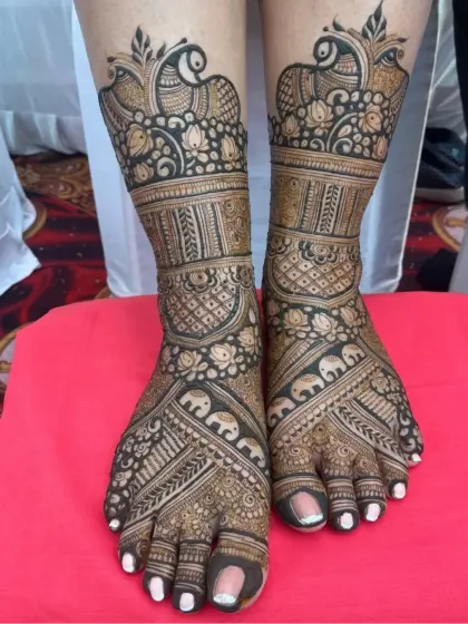 I create intricate designs for feet that are just as detailed as the hands. This piece features beautiful peacock and elephant motifs, along with fine jaali (net) patterns for a complete bridal look.
