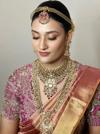 This is a masterclass in soft, natural bridal makeup. The focus is on glowing skin and subtly highlighted eyes, allowing the bride's elegance and the stunning jewelry to take center stage.