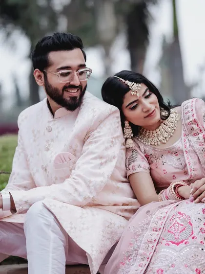 A serene and romantic pose with the bride-to-be resting on her partner's shoulder. This highlights the beautiful details of her lehenga and jewelry, creating a soft and elegant portrait.