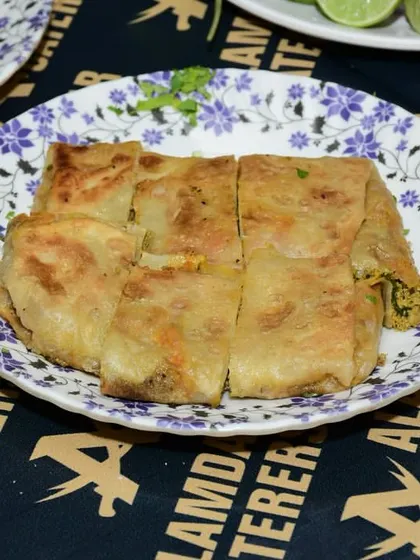 A plate of our delicious Baida Roti, cut into four pieces and ready to be shared. It's a classic street food dish that we make with care.