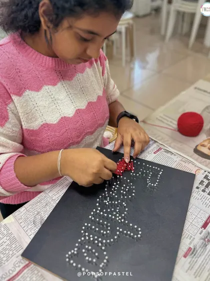 Adding the final touches to a custom name board, this participant weaves red string to create a heart.