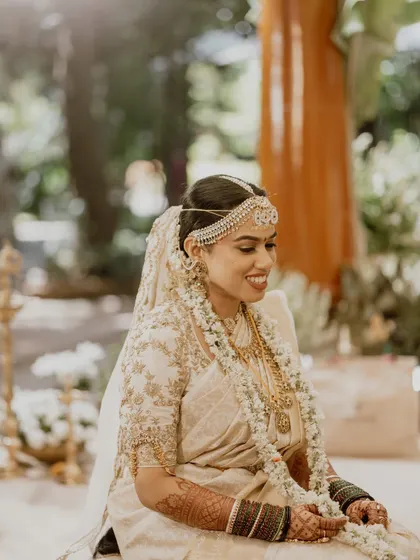 The serene glow of a Telugu-Malayali bride during her Muhurtham. I focused on creating a radiant, skin-focused look with subtly defined eyes, perfectly complementing her classic white and gold saree.