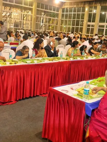 A closer view of the guests enjoying the meal. The vibrant colors of the sarees and the traditional food create a festive atmosphere.