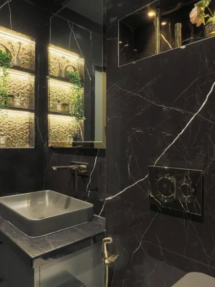 This powder room showcases the beauty of black marble. The backlit niches provide soft, ambient lighting, highlighting the decor and creating a warm, inviting glow against the dark, luxurious stone.