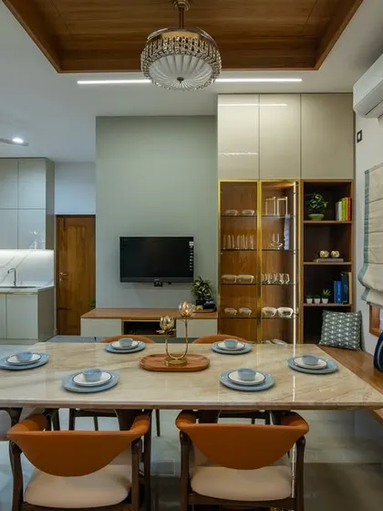 The dining space features a comfortable window seat, a marble-top table, and a wooden false ceiling with a traditional pendant light, creating a warm and inviting atmosphere for family meals.