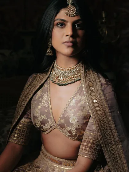 A beautiful close-up portrait of the bride, showcasing her stunning traditional jewelry and the intricate work on her designer blouse.