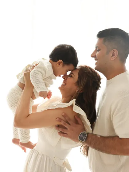 Pure joy in a single frame. A mother lifts her child up for a sweet nose-to-nose moment, creating a beautiful silhouette against the bright, airy studio background.