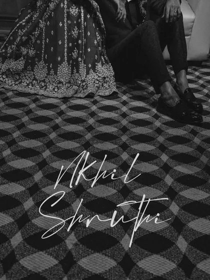 An artistic black and white shot focusing on the couple's feet and the hem of the bride's lehenga, with their names elegantly written over it.