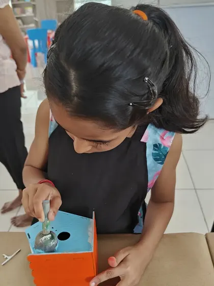 Close-up shot of a girl painting her birdhouse project during a fun artsy birthday party for her friend Emma.