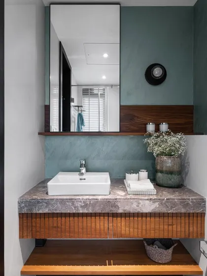 A dramatic makeover from drab to fab. This powder room combines a textured teal wall with warm wood accents and a fluted marble vanity to create a space that is rich in color, texture, and character.