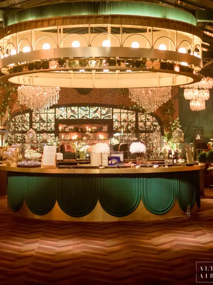The stunning circular bar at the glass house reception. The emerald green base, brass details, and grand light fixture above made it a glamorous hub for the evening.