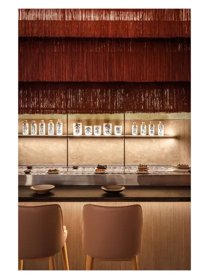 We used layered lighting to create drama and highlight details, as seen here at the sushi bar. The cascading tassel light adds a soft, whimsical texture above the sleek, modern counter.