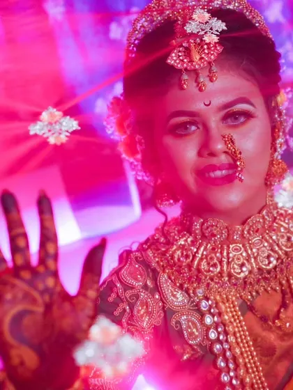 A creative bridal shot using dramatic pink lighting and a shallow depth of field to focus on the bride's expression and mehendi.