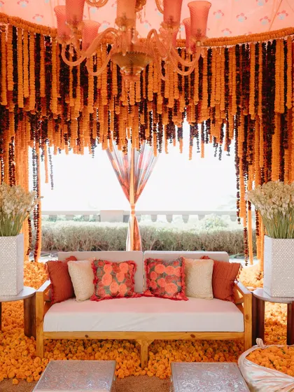 A cozy seating nook inside a tent made entirely of orange marigolds. This immersive design created a warm and vibrant space for a Mehendi in Udaipur.