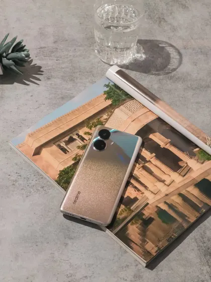 The realme 10 Pro+ 5G placed on an open magazine, with the phone's design complementing the page layout.