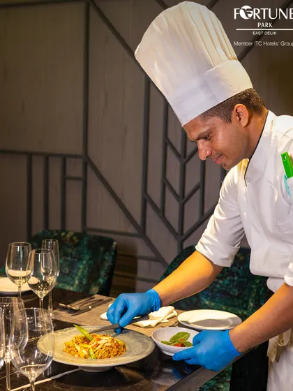 Our chef adds a delicate garnish to a plate of noodles, showcasing the attention to detail that goes into every dish we serve.