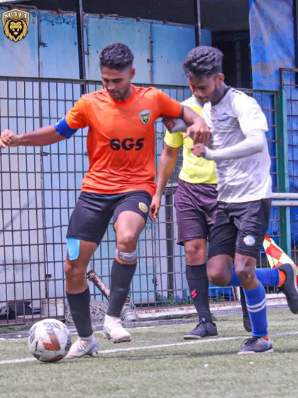 A player shielding the ball under pressure during the MFA First Division match. Ball control and strength are key skills we develop.