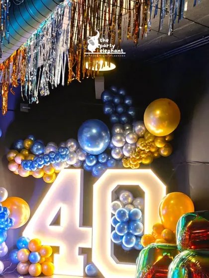 Another angle of the marquee '40', surrounded by a sea of metallic blue, gold, and silver balloons. The lighting and reflective surfaces created a vibrant and celebratory atmosphere.