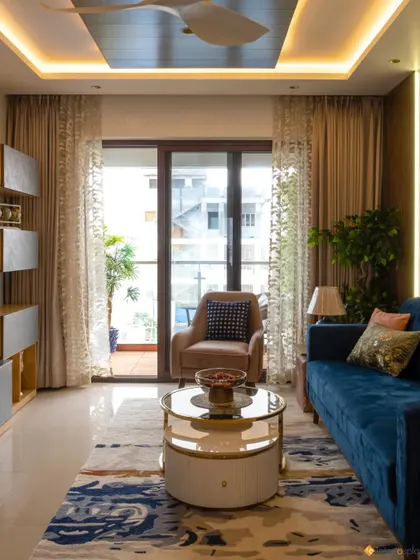 This living room is designed for comfort and style, with a plush blue sofa, a modern coffee table, and large windows dressed with elegant curtains that let in plenty of natural light.