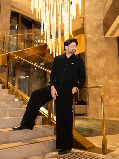 The architectural details of the staircase complement the clean lines of the custom-fit outfit, creating a very strong and stylish image.