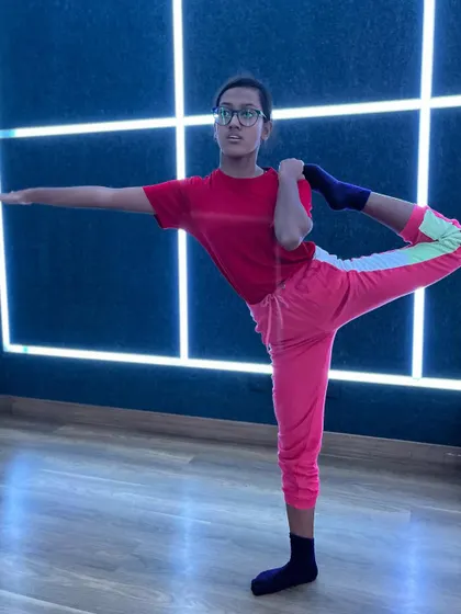A student practices a standing yoga pose, demonstrating balance and focus in our modern studio.