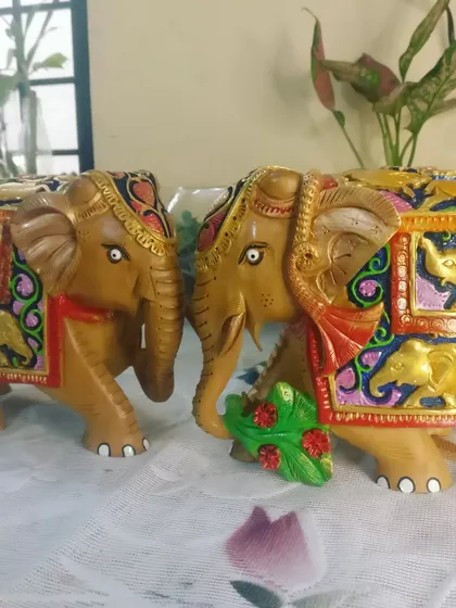 A front view of the pair of painted wooden elephants.