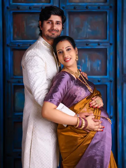 A classic portrait of the couple against a striking blue door. The mother-to-be, dressed in a traditional Odia saree, is embraced by her partner.
