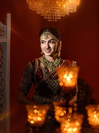 A beautiful candid moment, framed by the warm glow of candles. This shot captures the bride's natural smile and the festive ambiance of a wedding celebration.