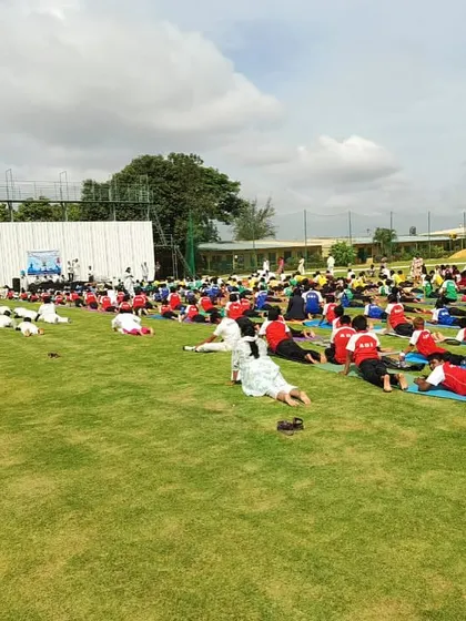 A wide shot of our students engaged in a guided yoga and stretching session on the field, an essential part of their daily warm-up routine.