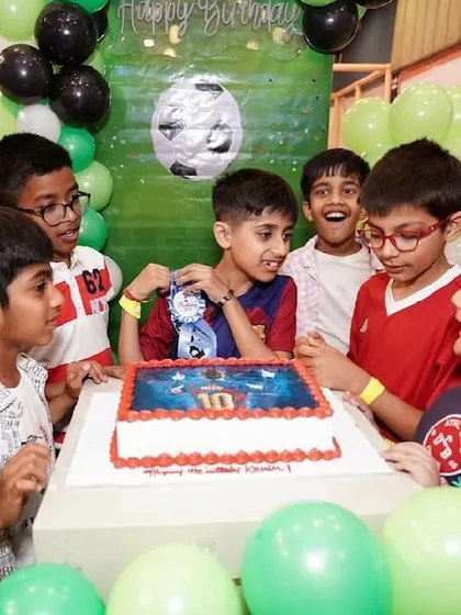 The birthday boy and his friends gather around a football-themed cake, ready to celebrate.